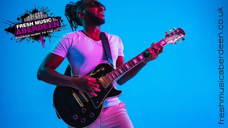 Guitarist playing an electric guitar against a blue backdrop beside the Fresh Music Aberdeen logo